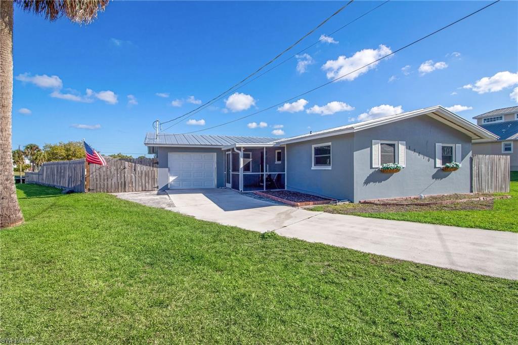 View of front of property with stucco siding, concrete driveway, an attached garage, and a metal roof