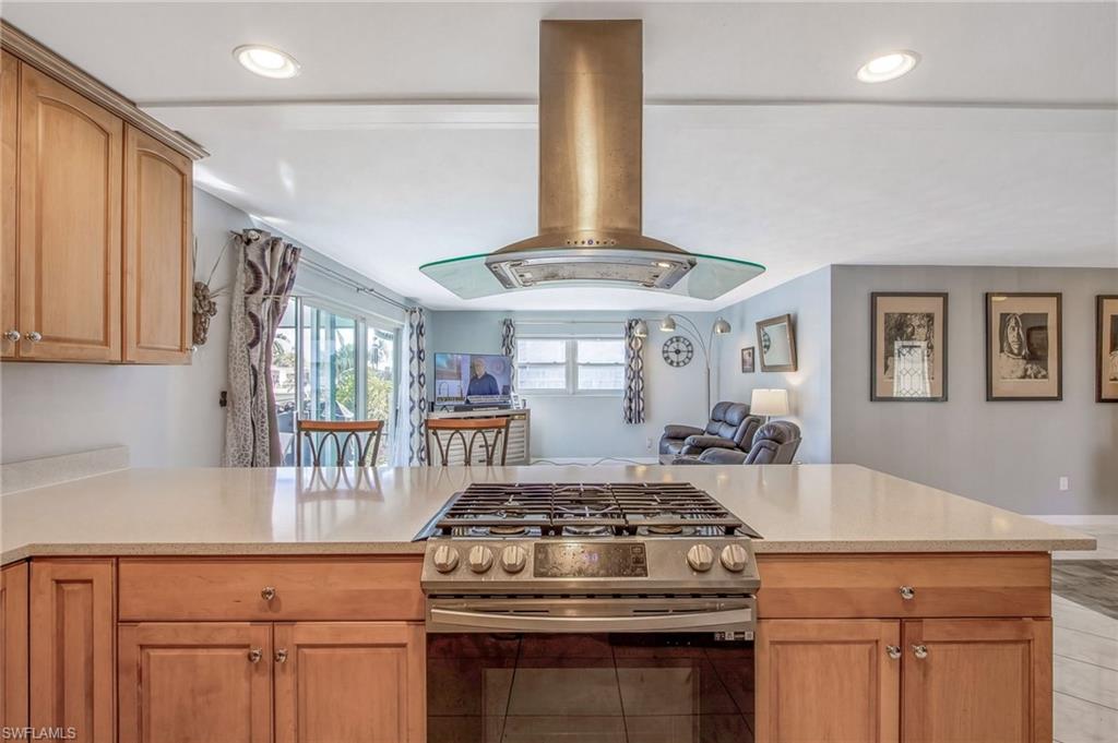 Kitchen featuring gas range, island exhaust hood, open floor plan, a peninsula, and recessed lighting