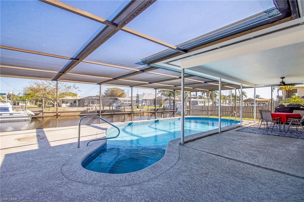 View of swimming pool with glass enclosure, a residential view, patio surround, outdoor dining area, and a water view