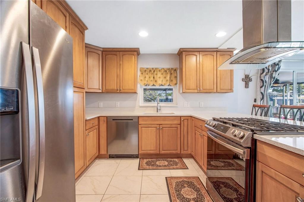 Kitchen featuring stainless steel appliances, island range hood, recessed lighting, light stone counters, and wood finish cabinets