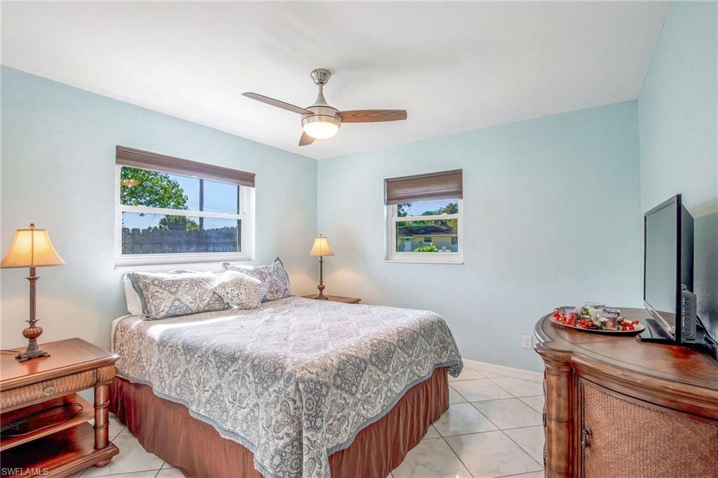 Bedroom with ceiling fan, multiple windows, and light tile patterned flooring