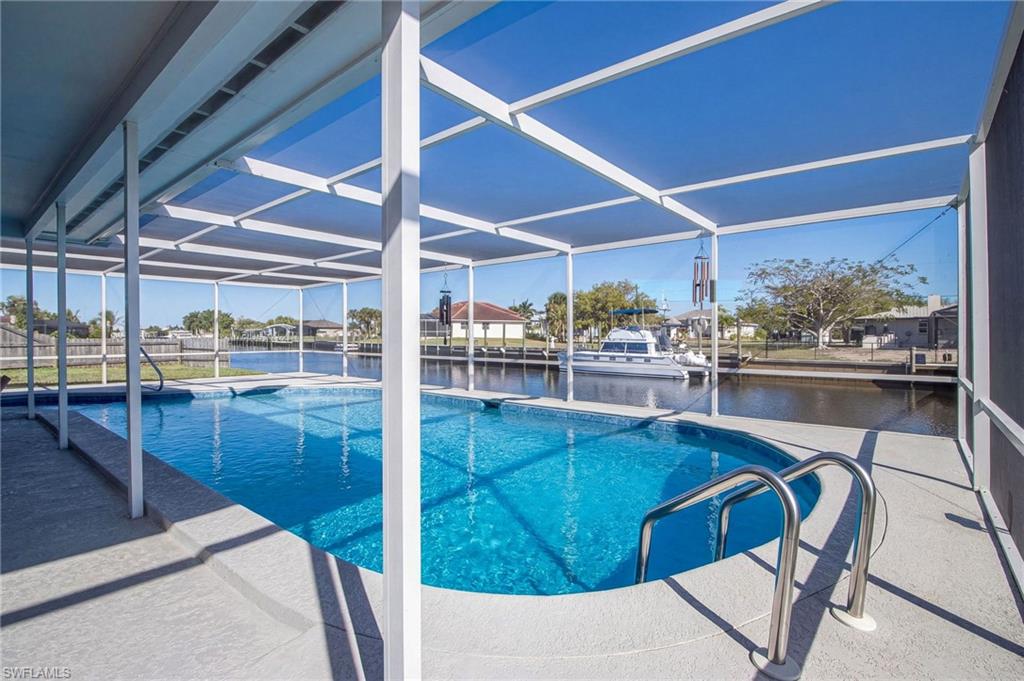 Outdoor pool featuring glass enclosure, a water view, a patio, and a dock