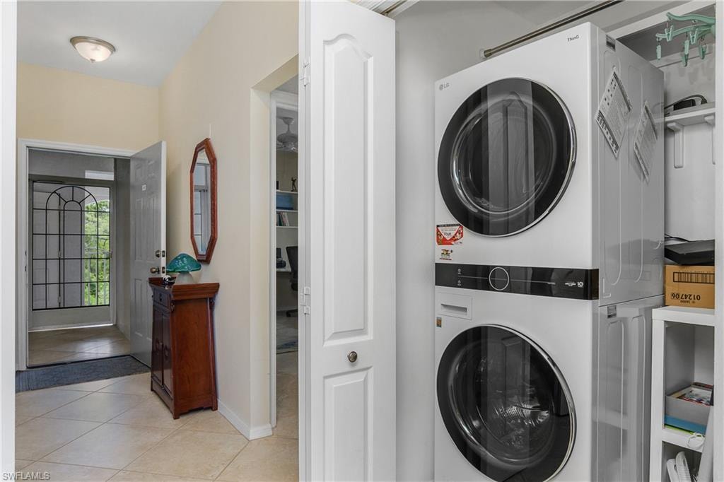 Washroom with laundry area, stacked washer and dryer, baseboards, and light tile patterned floors