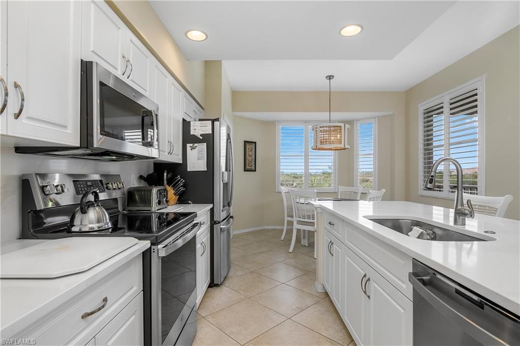 Kitchen with baseboards, a sink, white cabinets, and stainless steel appliances