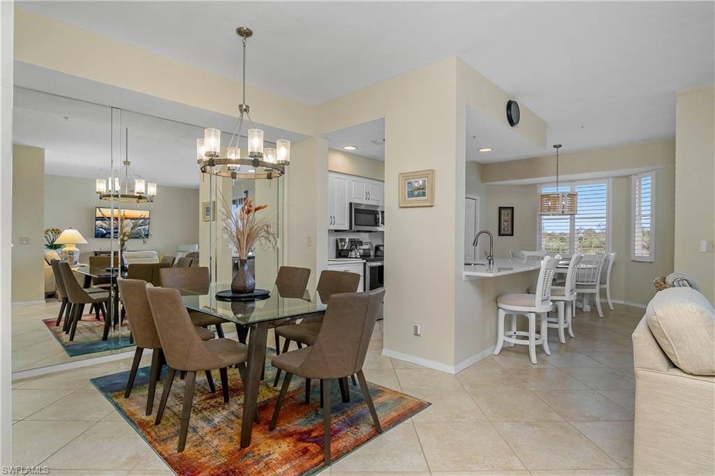 Dining space with baseboards, a notable chandelier, and light tile patterned floors