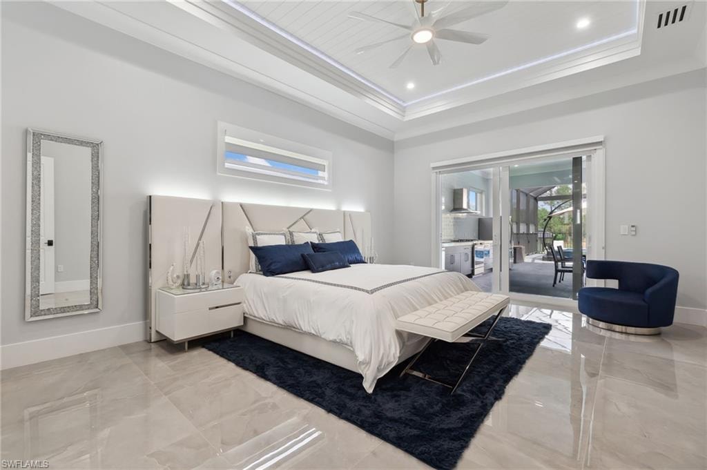 Bedroom with a tray ceiling, baseboards, crown molding, and access to outside