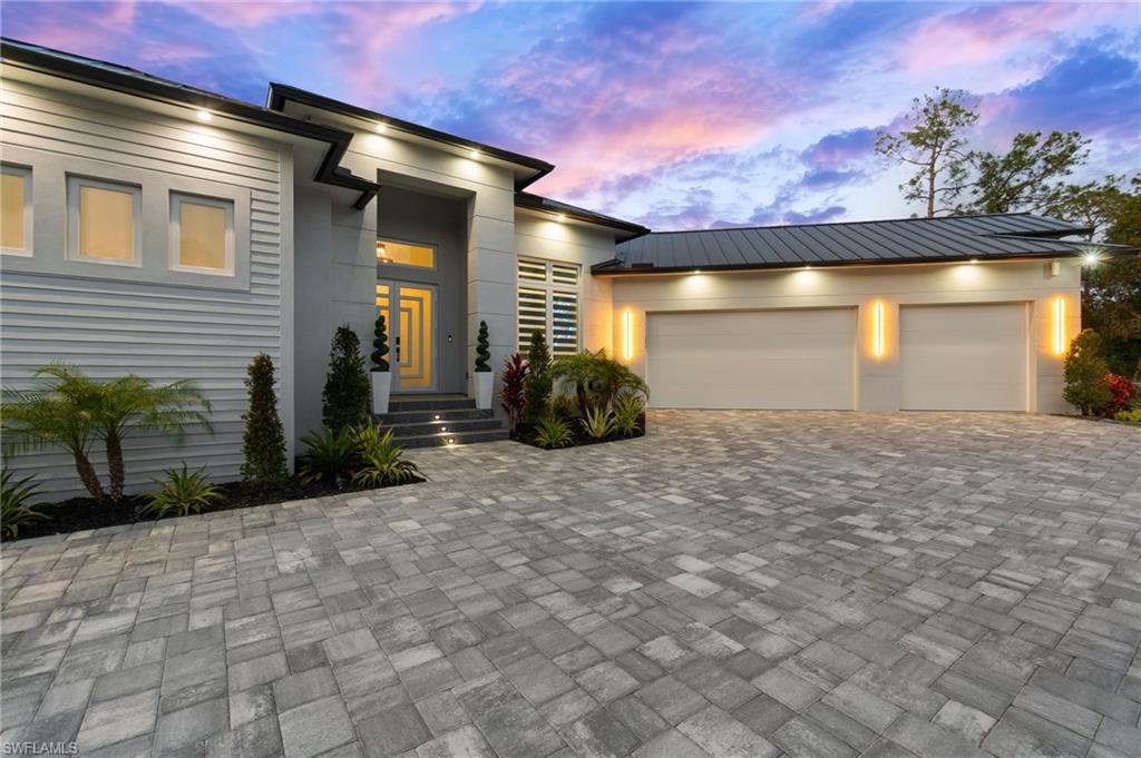 View of front facade featuring decorative driveway, a garage, metal roof, and stucco siding
