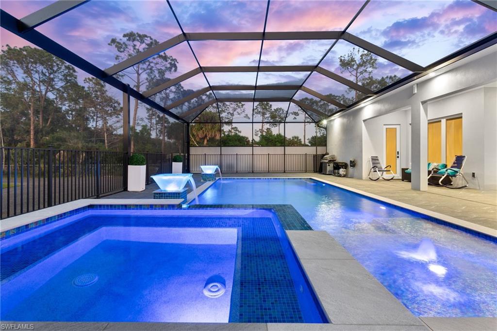 View of pool featuring a fenced in pool, fence, glass enclosure, a patio area, and an in ground hot tub