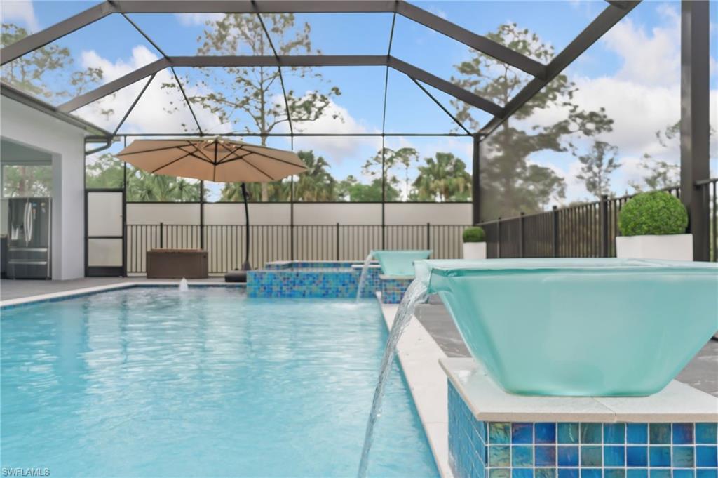 View of pool featuring a fenced in pool, fence, a lanai, a jacuzzi, and a patio