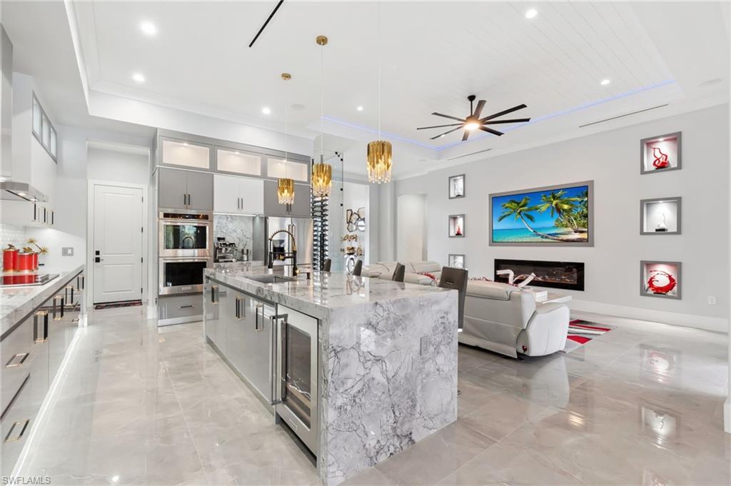 Kitchen with black electric stovetop, double oven, modern cabinets, and a tray ceiling