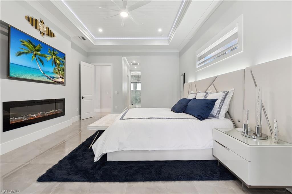Bedroom with baseboards, visible vents, a tray ceiling, recessed lighting, and ornamental molding