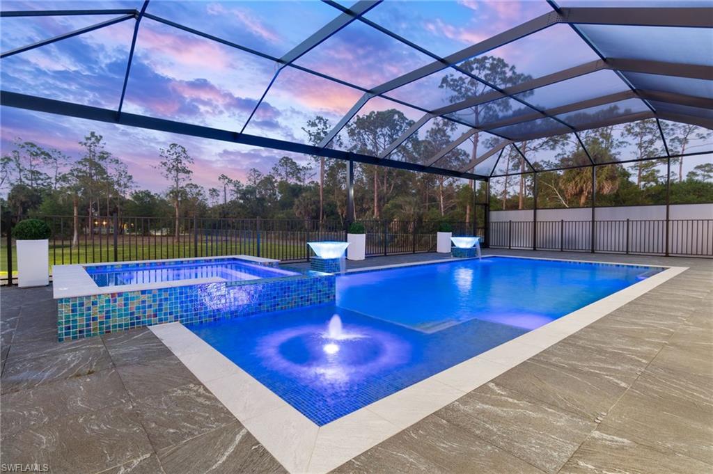 Pool at dusk featuring a lanai, a patio, and fence