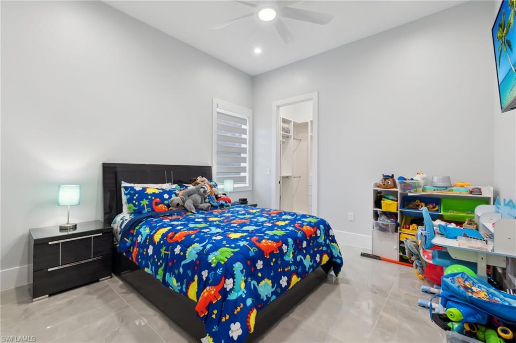 Bedroom with a ceiling fan, a walk in closet, and baseboards