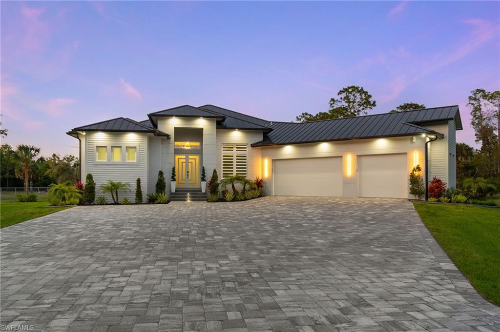 View of front facade featuring a garage, metal roof, decorative driveway, and a standing seam roof