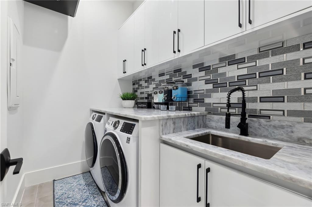 Washroom with baseboards, cabinet space, a sink, tile patterned floors, and independent washer and dryer