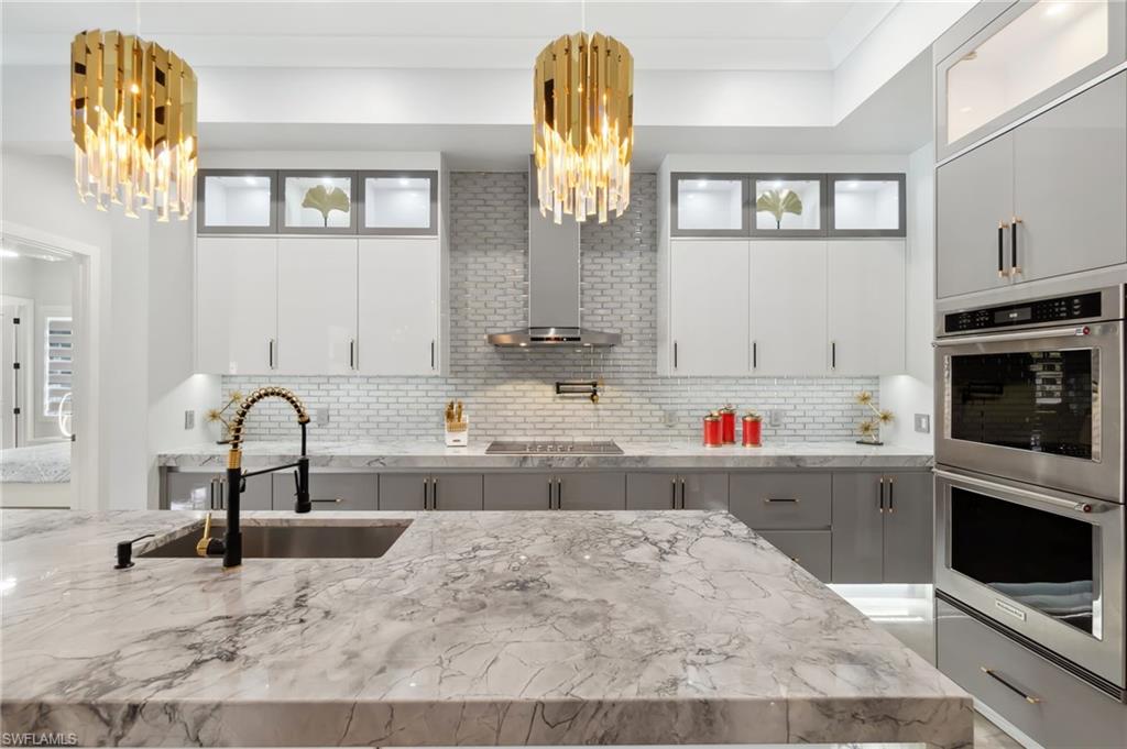 Kitchen with a sink, decorative backsplash, stainless steel double oven, and a chandelier