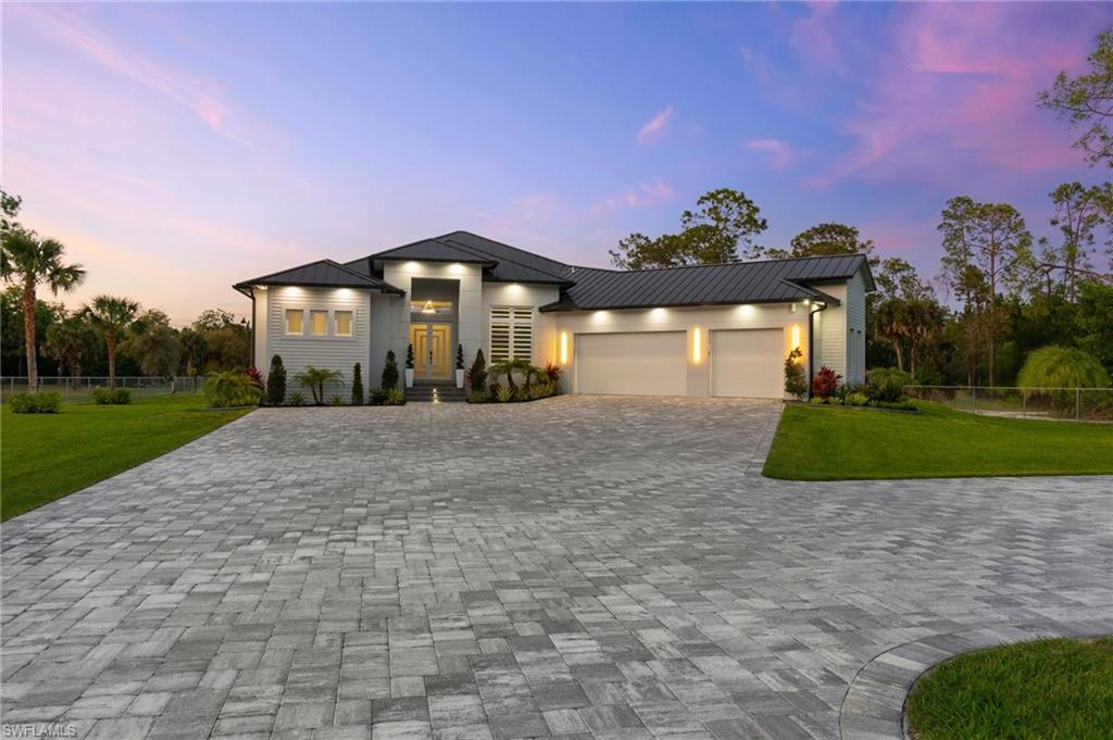 View of front of property featuring a standing seam roof, decorative driveway, a lawn, and metal roof
