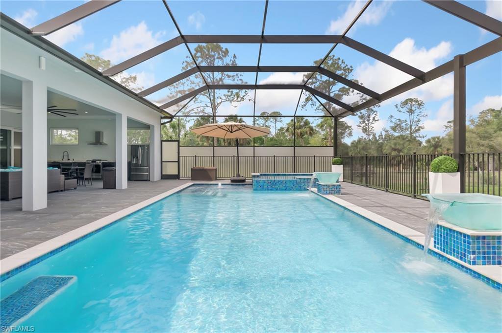 View of swimming pool featuring glass enclosure, a fenced in pool, an in ground hot tub, ceiling fan, and a patio area