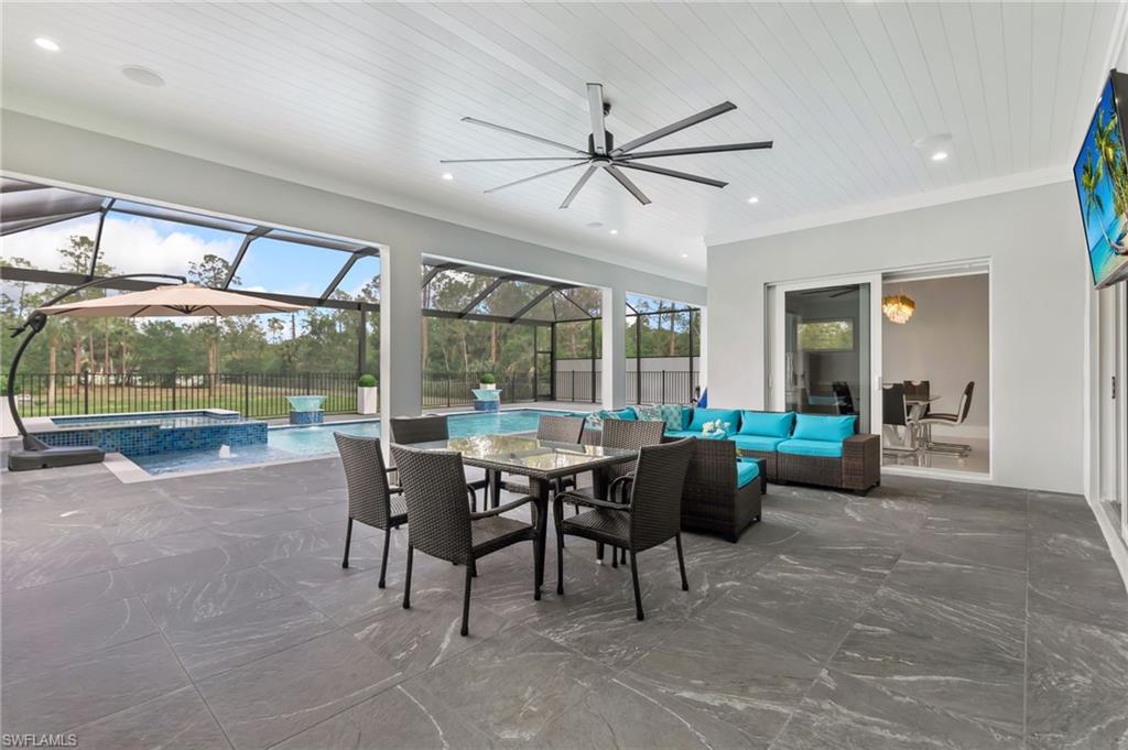 View of patio / terrace featuring glass enclosure, a ceiling fan, fence, an outdoor living space, and outdoor dining area