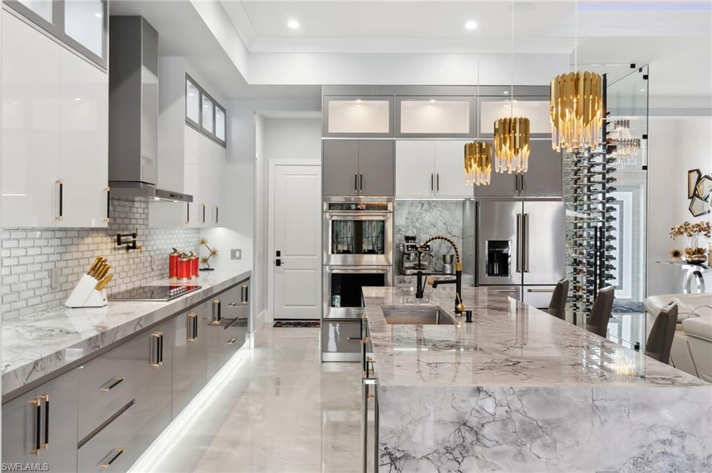 Kitchen featuring gray cabinetry, a sink, appliances with stainless steel finishes, wall chimney exhaust hood, and modern cabinets