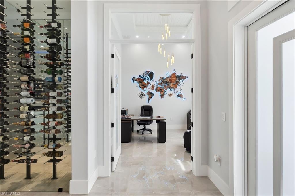 Wine cellar featuring an inviting chandelier, baseboards, and marble finish floor