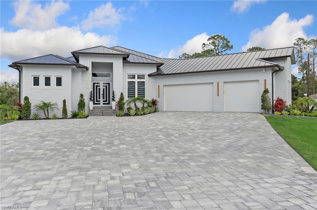 View of front of home featuring an attached garage, metal roof, decorative driveway, and a standing seam roof