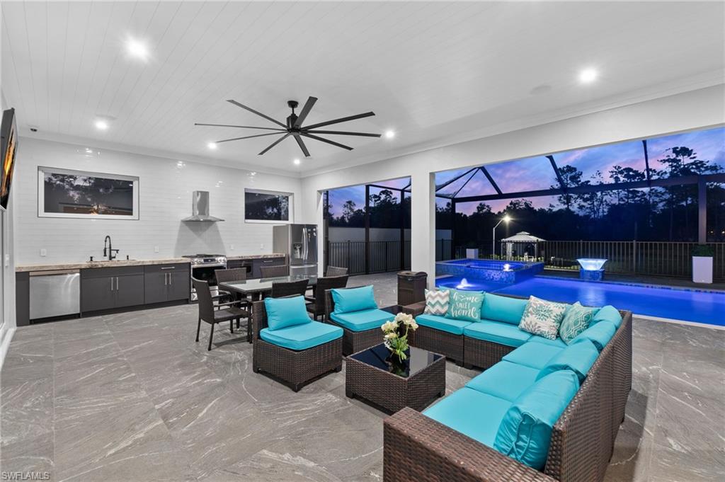 View of patio featuring glass enclosure, exterior kitchen, an in ground hot tub, a sink, and an outdoor hangout area
