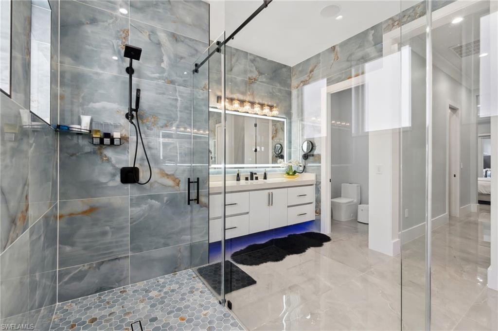 Bathroom featuring vanity, a shower stall, toilet, and visible vents