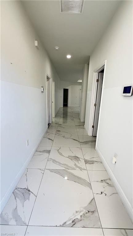 Corridor featuring baseboards and light marble finish flooring