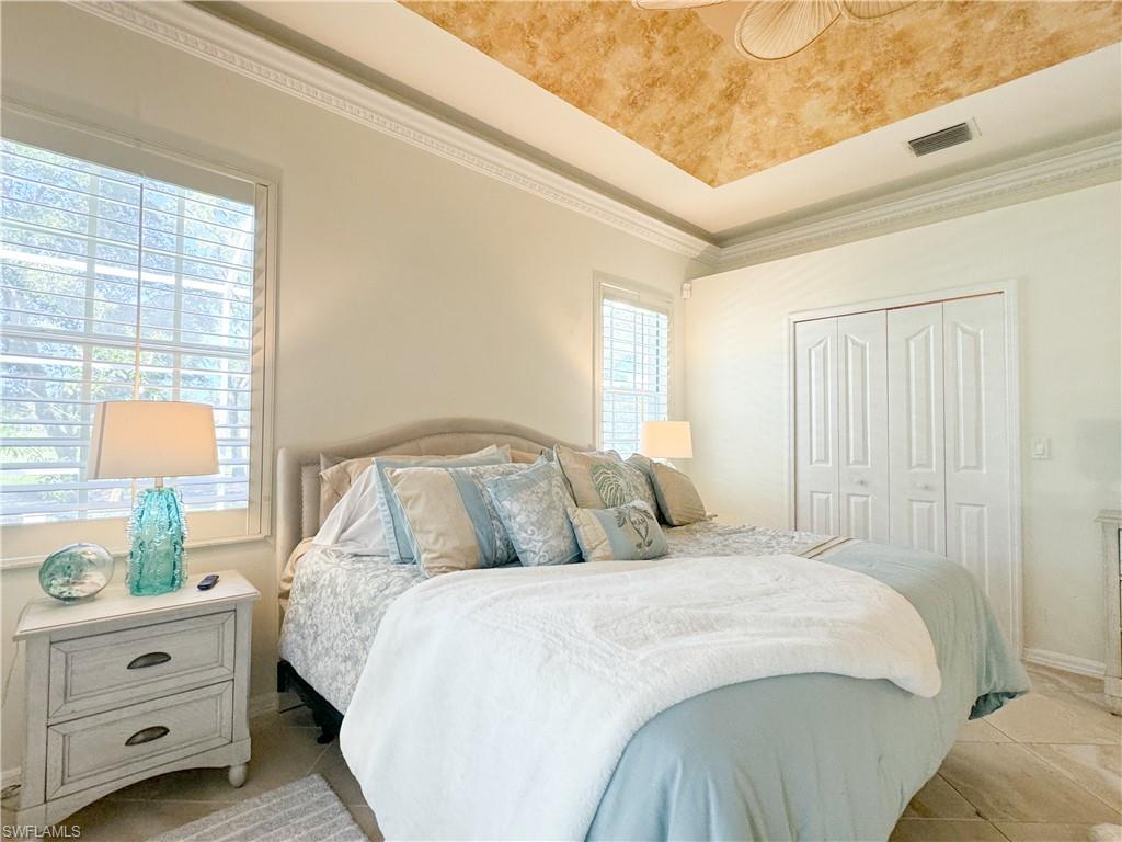 Bedroom with ornamental molding, a closet, and multiple windows