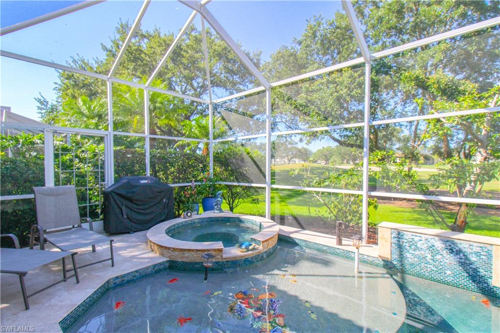 View of swimming pool featuring an in ground hot tub, glass enclosure, a patio area, and grilling area