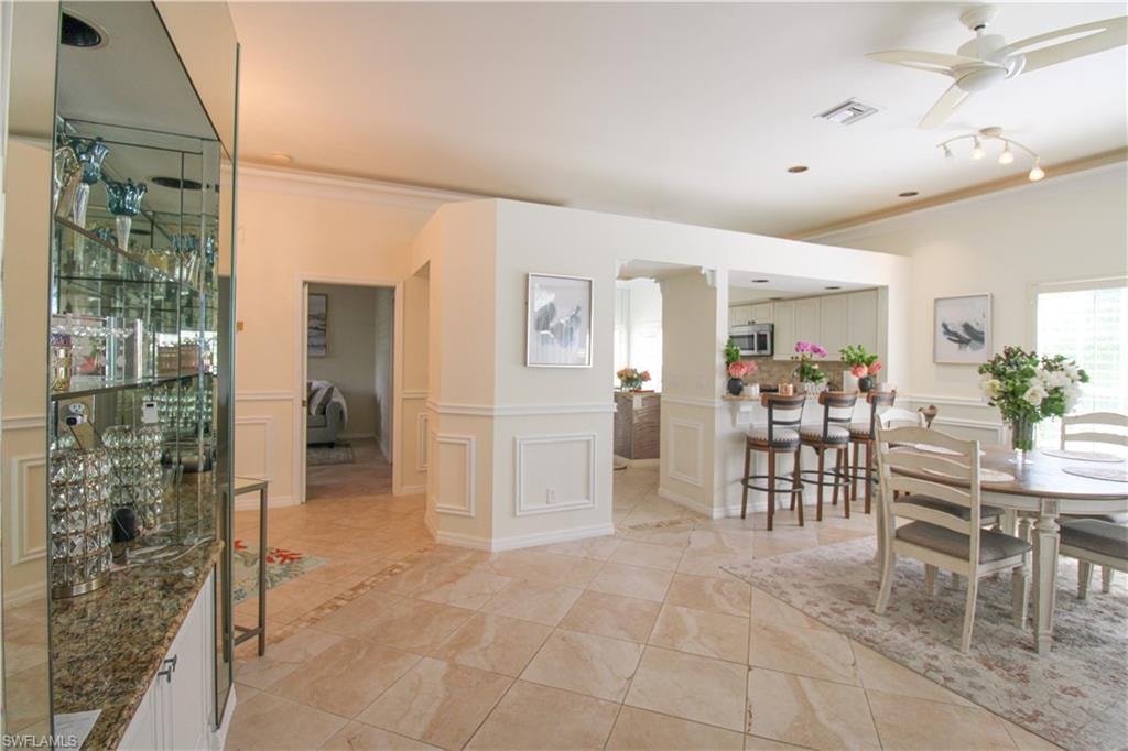 Dining room featuring ceiling fan, ornamental molding, and light tile floors