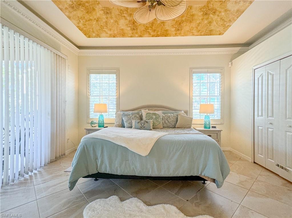 Tiled bedroom with a tray ceiling, a closet, and ceiling fan