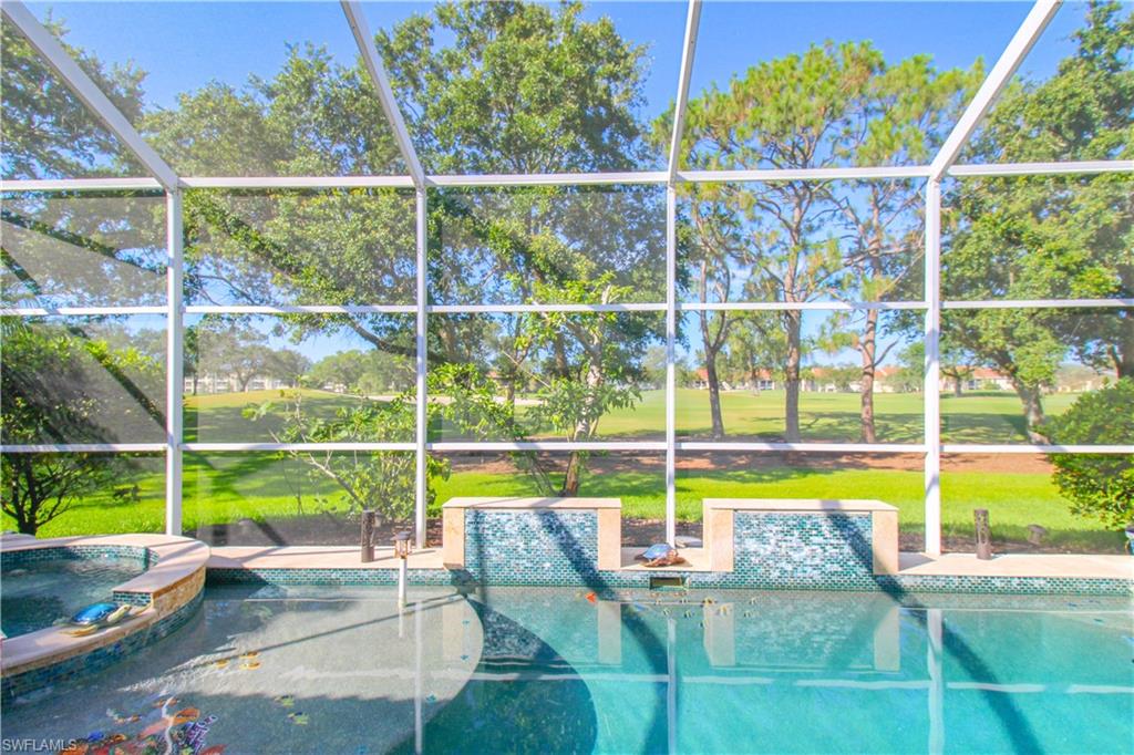 View of swimming pool featuring a patio, glass enclosure, and an in ground hot tub