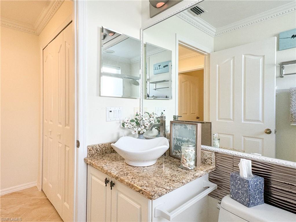 Bathroom featuring ornamental molding, tile flooring, toilet, and vanity