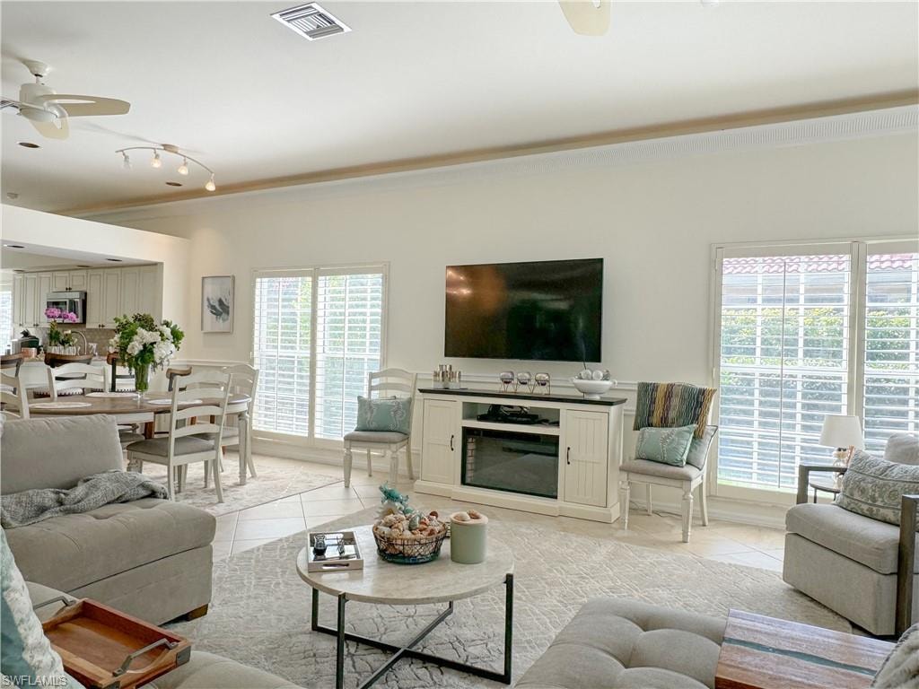 Living room with a healthy amount of sunlight, track lighting, ceiling fan, and light tile floors