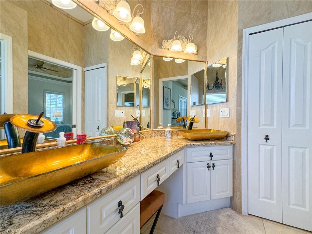 Bathroom with tile flooring, ceiling fan, oversized vanity, and dual sinks