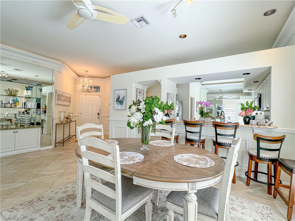 Dining space featuring crown molding, light tile floors, and ceiling fan with notable chandelier