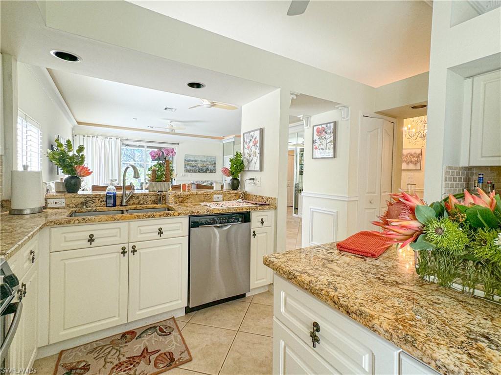 Kitchen with white cabinetry, appliances with stainless steel finishes, sink, ceiling fan, and light tile floors