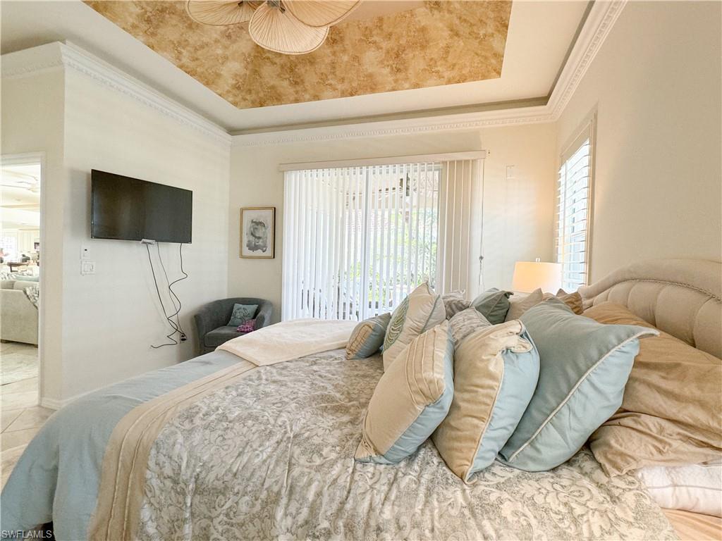 Tiled bedroom featuring ornamental molding and a raised ceiling