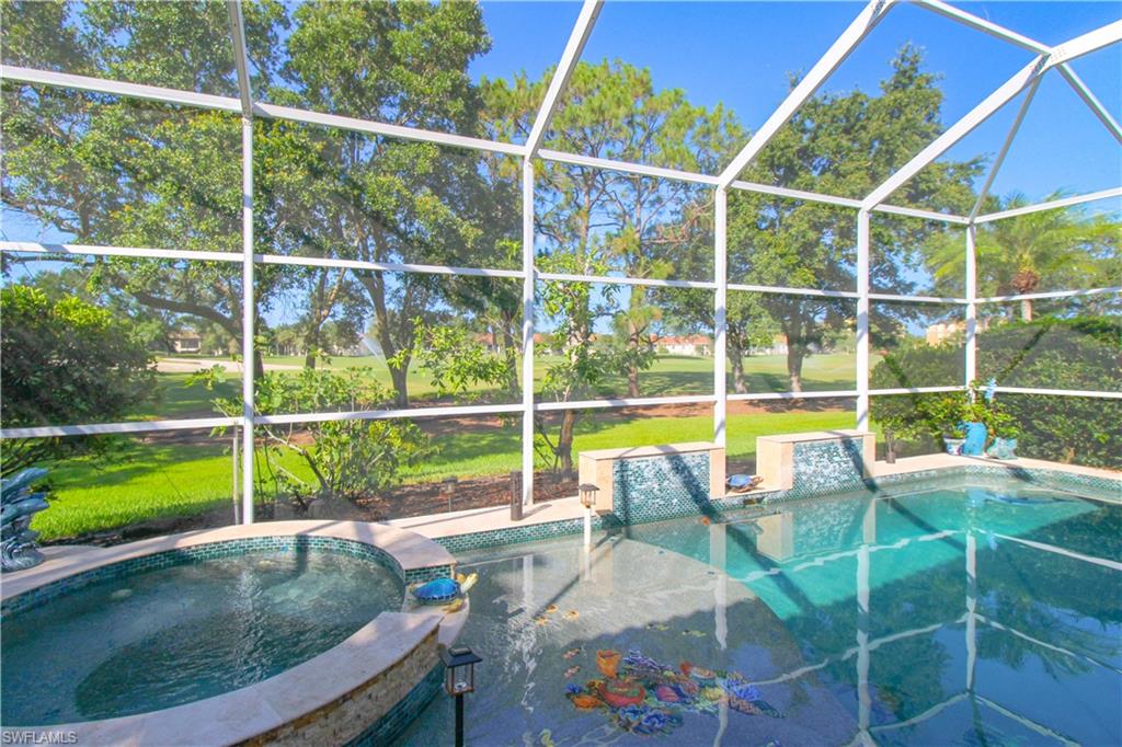 View of swimming pool featuring glass enclosure, an in ground hot tub, area for grilling, and a lawn