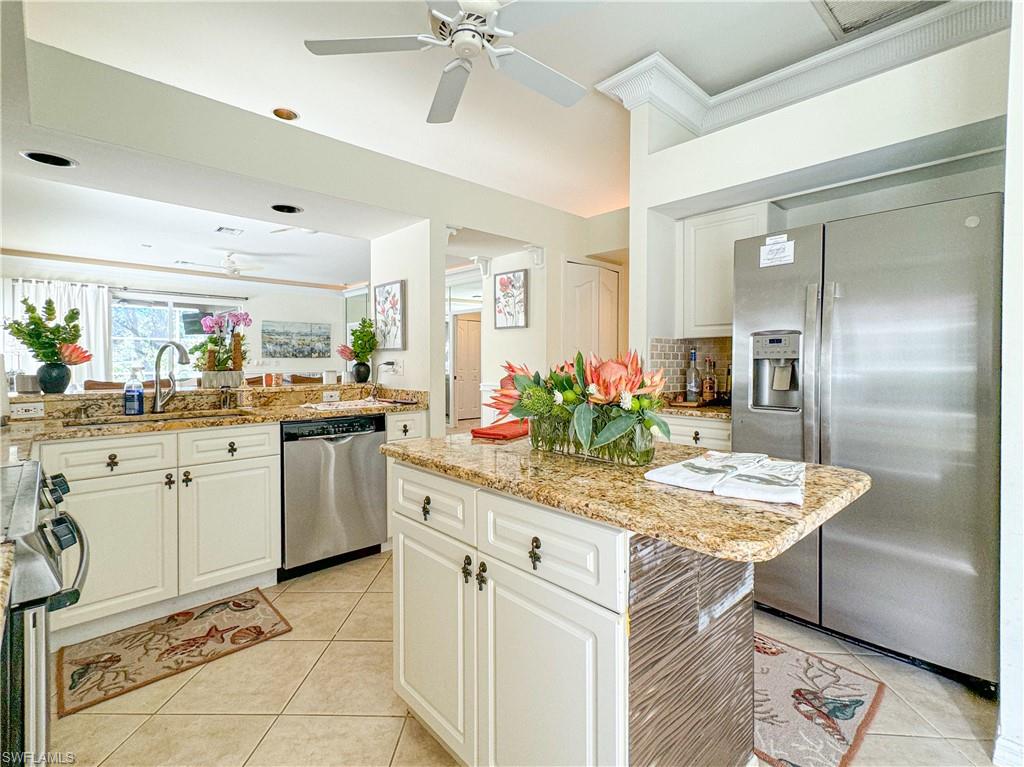Kitchen featuring a kitchen island, stainless steel appliances, tasteful backsplash, ceiling fan, and light tile floors