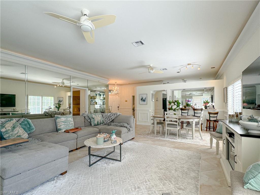 Living room with plenty of natural light, ceiling fan, crown molding, and light tile floors