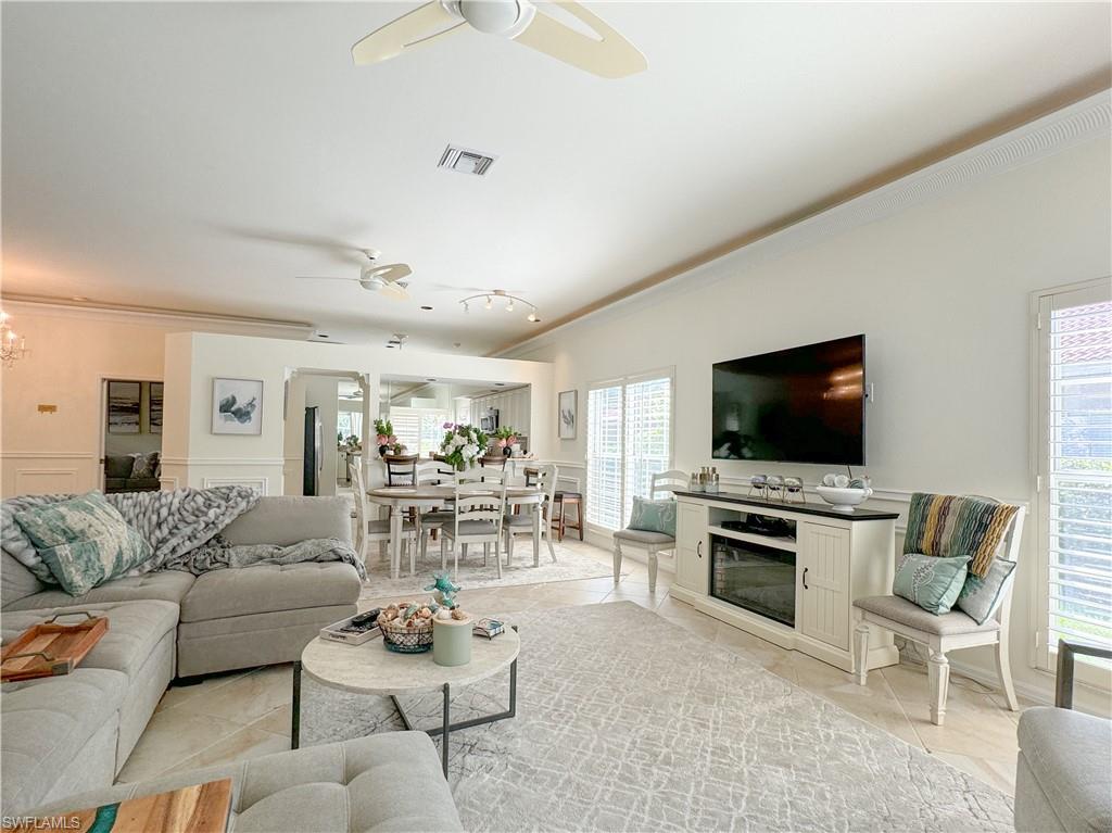 Living room with ceiling fan, crown molding, and light tile floors