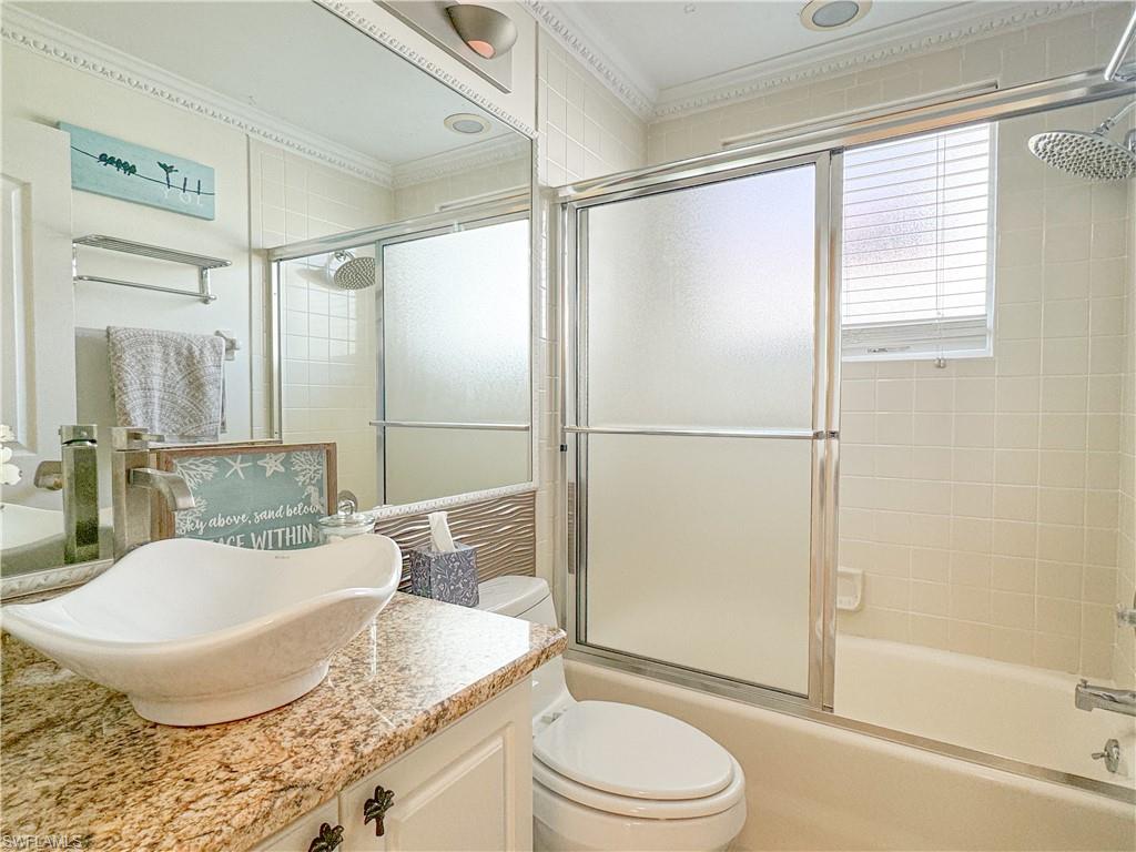Full bathroom featuring crown molding, toilet, combined bath / shower with glass door, and oversized vanity