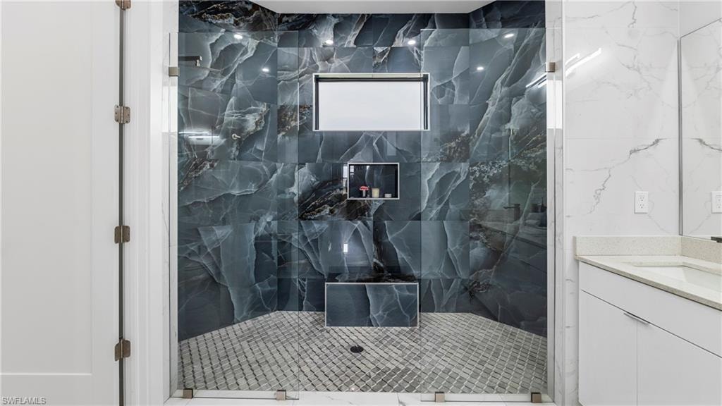 Full bath featuring a marble finish shower and vanity