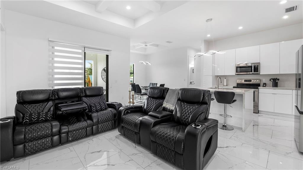 Cinema with recessed lighting, coffered ceiling, light marble finish flooring, and a ceiling fan