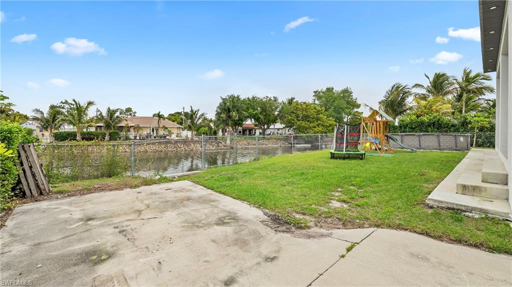Fenced yard with a water view, a patio area, and a playground