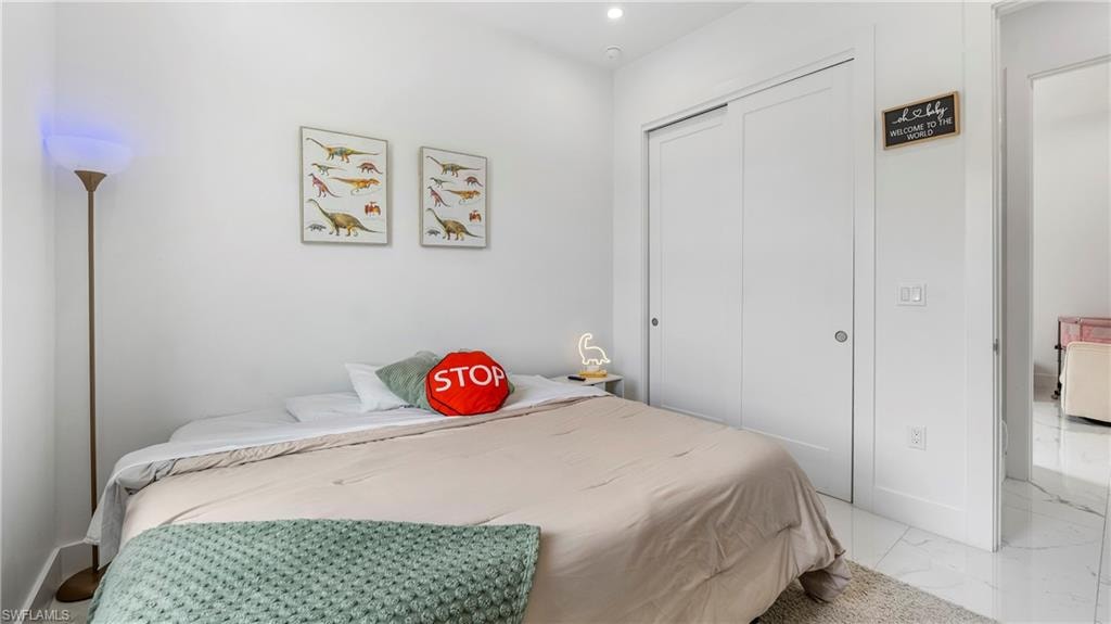 Bedroom featuring a closet, recessed lighting, and light marble finish floors