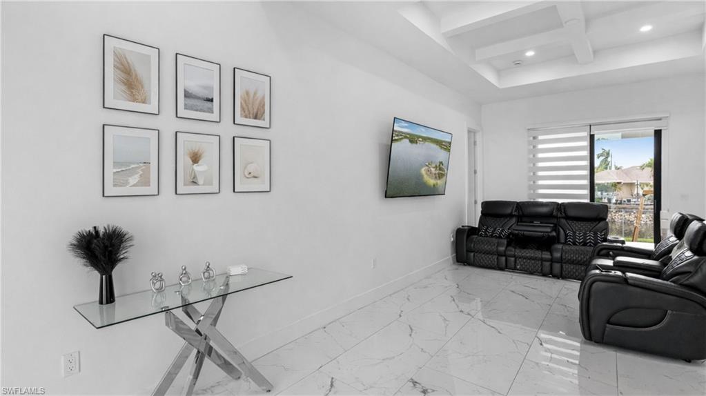 Living area featuring coffered ceiling, recessed lighting, and light marble finish floors